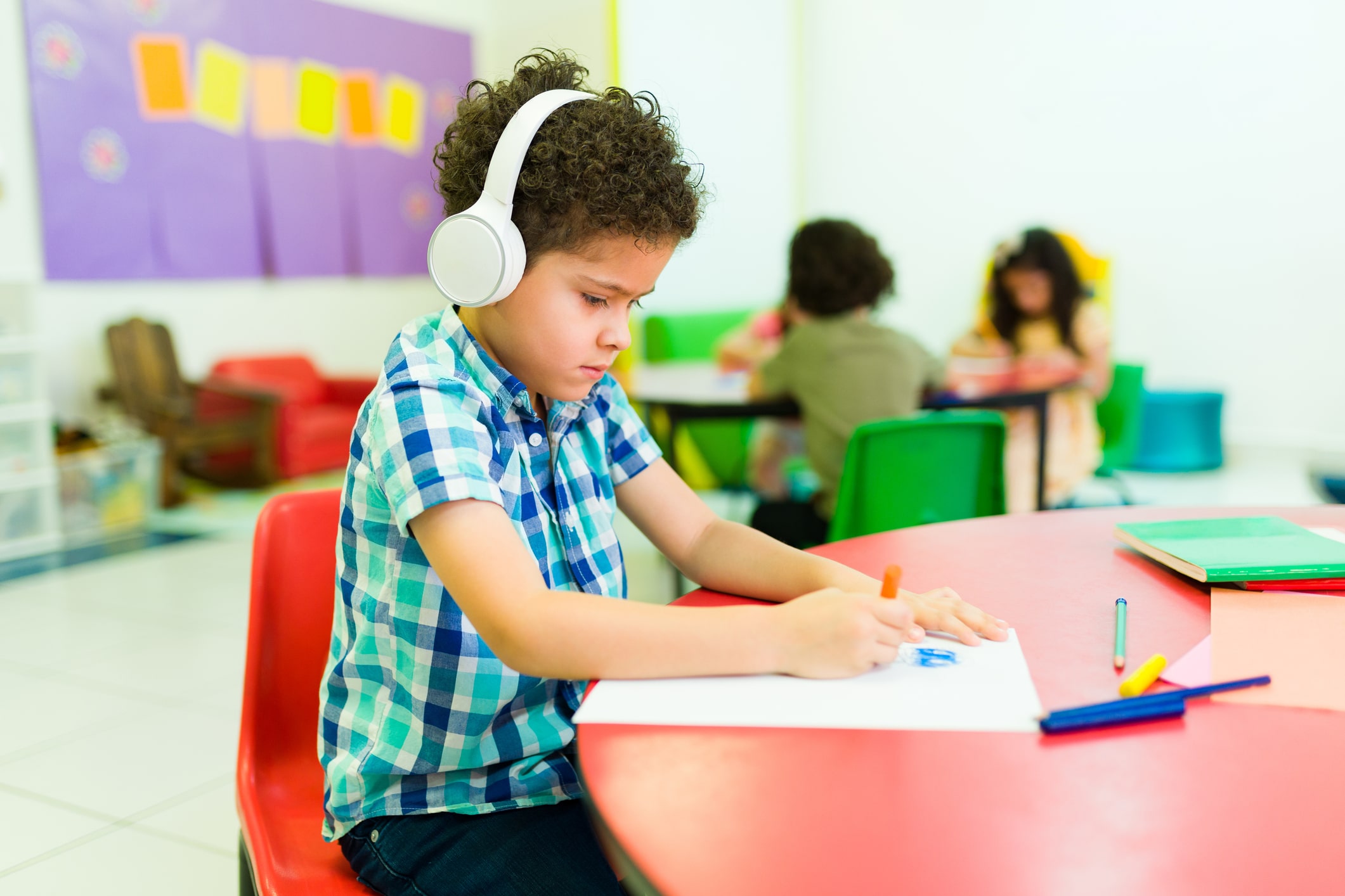 little boy with headphones on coloring a picture