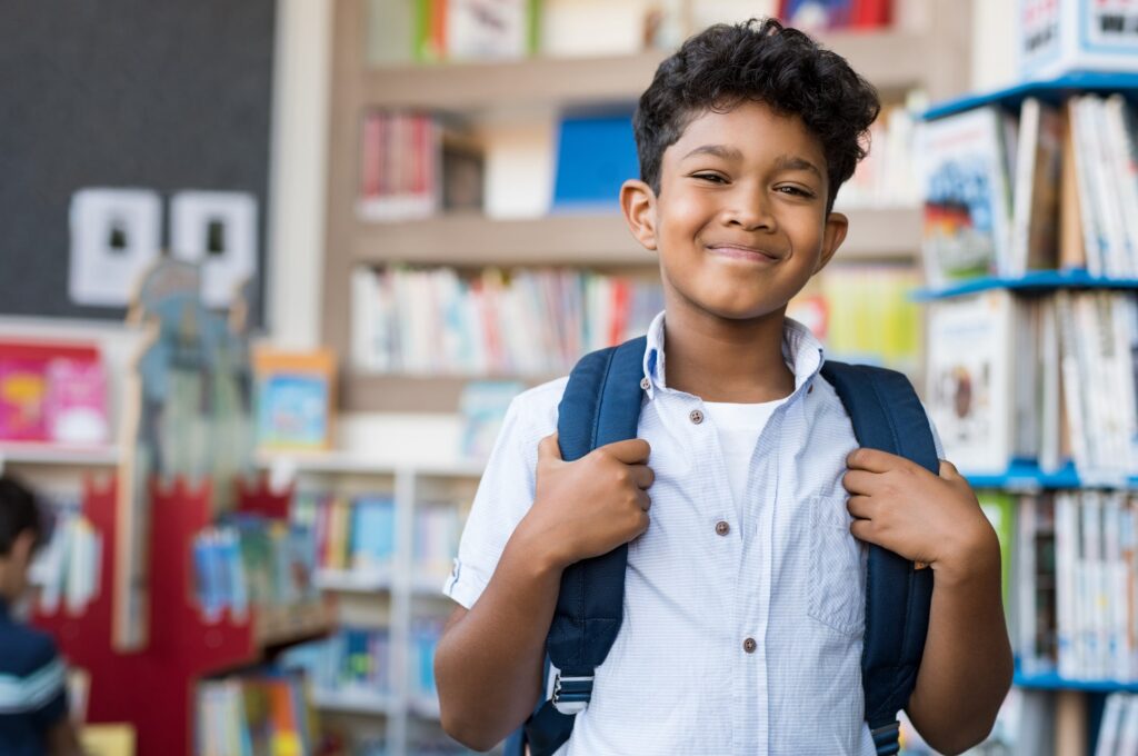 little boy with backpack on at school